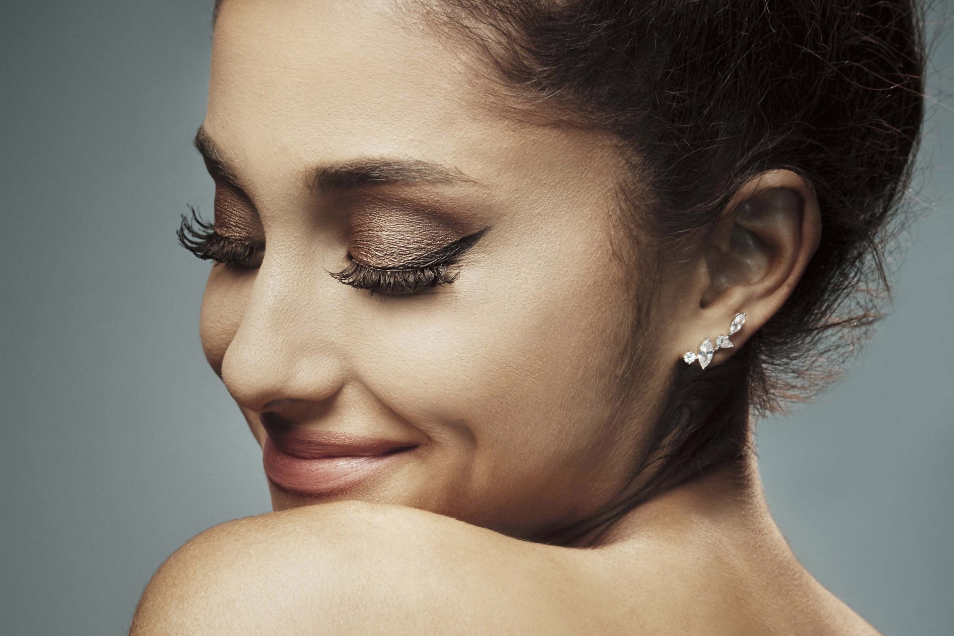 Close-up HD desktop wallpaper of brunette singer Ariana Grande, showcasing her serene smile and elegant makeup.