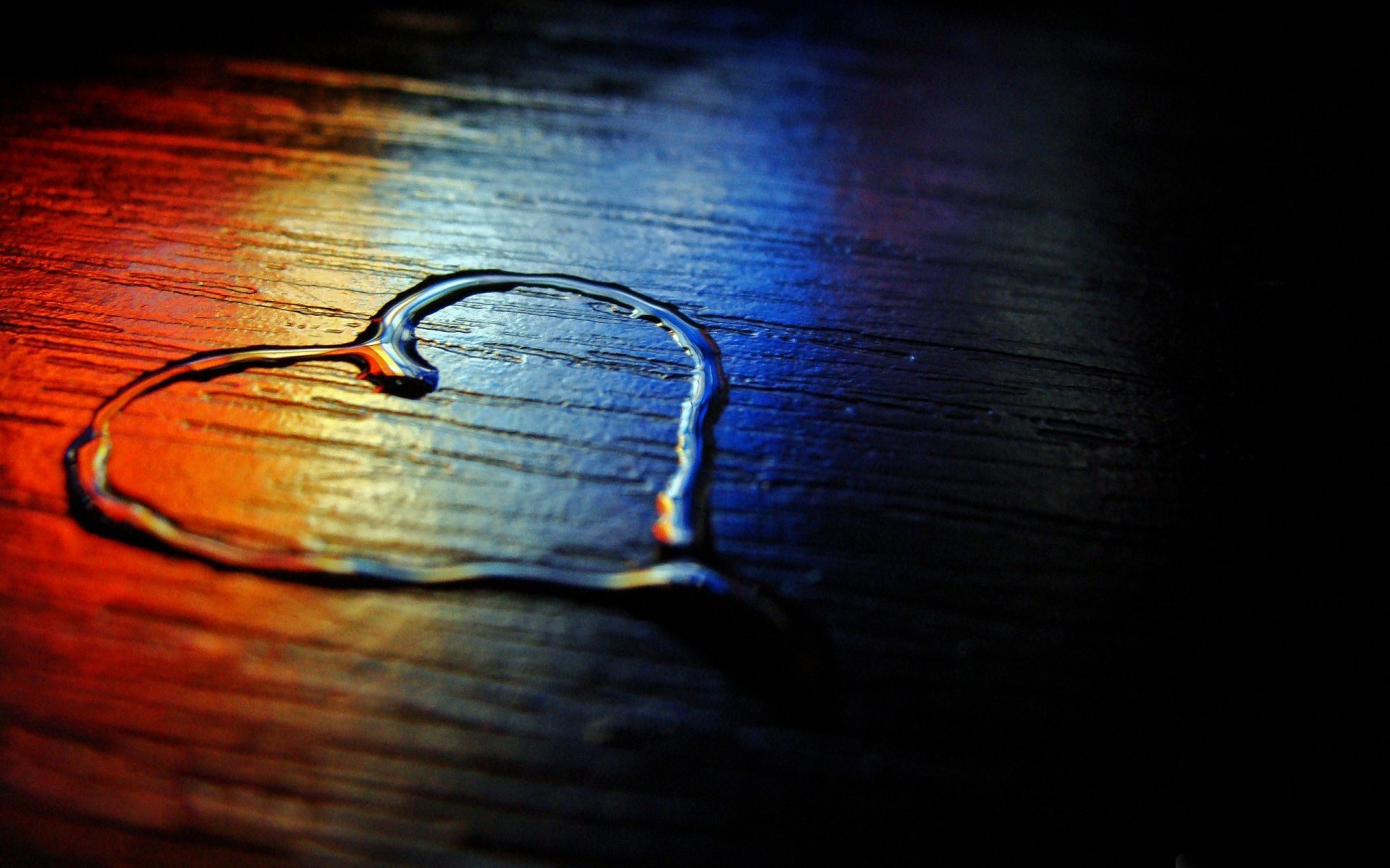 Artistic HD wallpaper of a heart shape outlined with water on a wooden surface, illuminated by colorful light, evoking a sense of love.