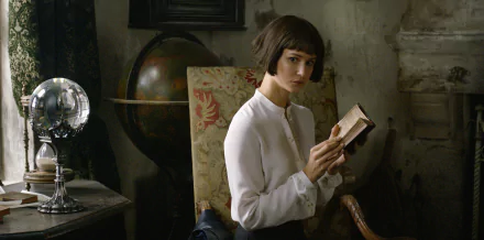 HD wallpaper featuring a pensive individual with a short haircut, clad in a white shirt, holding a book in a vintage-styled room with antique decor.