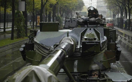 HD desktop wallpaper featuring a close-up view of a military tank on a city street during daytime with soldiers visible inside.
