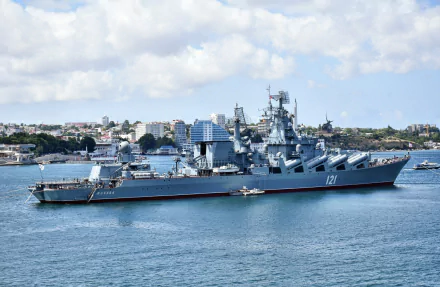 HD desktop wallpaper featuring the Russian cruiser Moskva, a military naval ship, docked near a coastal city under a partly cloudy sky.