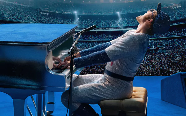 Taron Egerton as Rocketman in a stadium, passionately playing piano and singing into a microphone, captured in a vibrant 4K Ultra HD movie scene from RocketMan (2019).