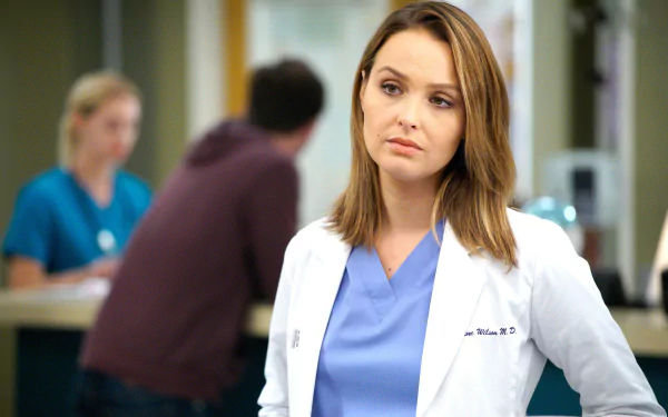 HD desktop wallpaper featuring a character from Grey's Anatomy, in a white lab coat, against a hospital backdrop.