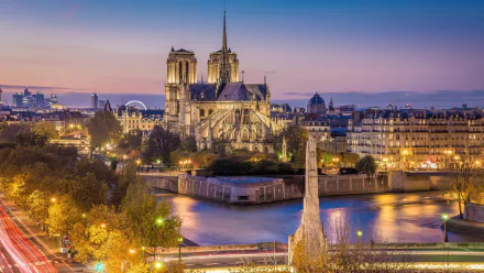 HD desktop wallpaper showcasing the iconic Notre-Dame de Paris cathedral at dusk, highlighting its Gothic architecture and the surrounding Paris cityscape.