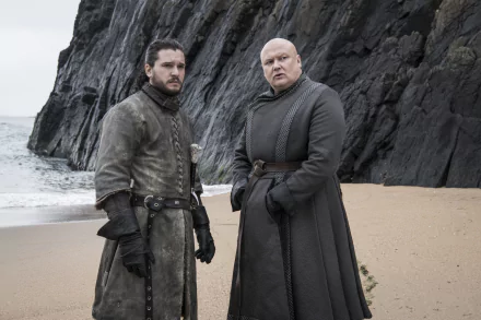 Game of Thrones 2K Quad HD desktop wallpaper: a brooding swordsman and a bald advisor in dark cloaks stand on a windswept rocky beach.