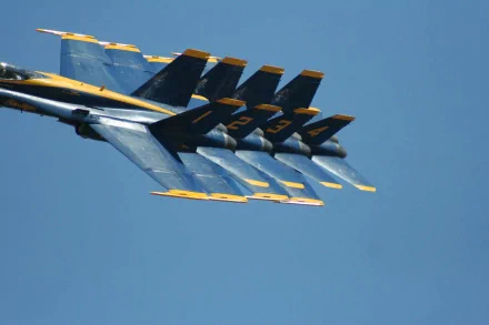 HD desktop wallpaper showing a close-up of military aircraft jet fighters flying in tight formation against a clear blue sky.