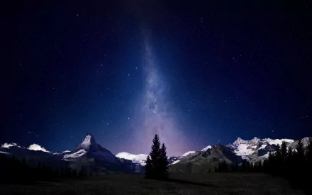 HD desktop wallpaper of a starry night sky over a mountain range, featuring a striking central peak and a vivid Milky Way. Image showcases digital manipulation for a captivating visual effect.