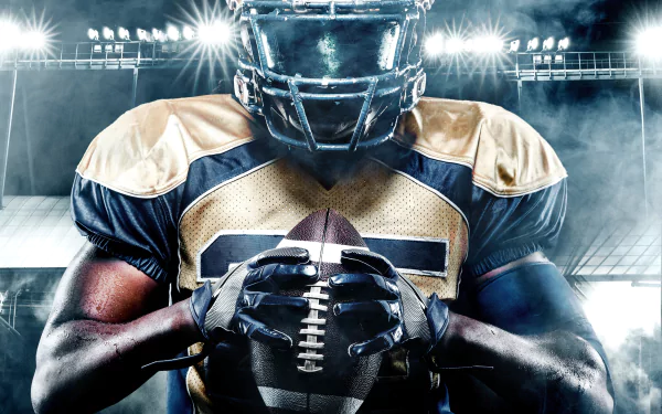Intense close-up of a football player clutching a ball under stadium lights — Sports 5K Ultra HD PC desktop wallpaper and background.