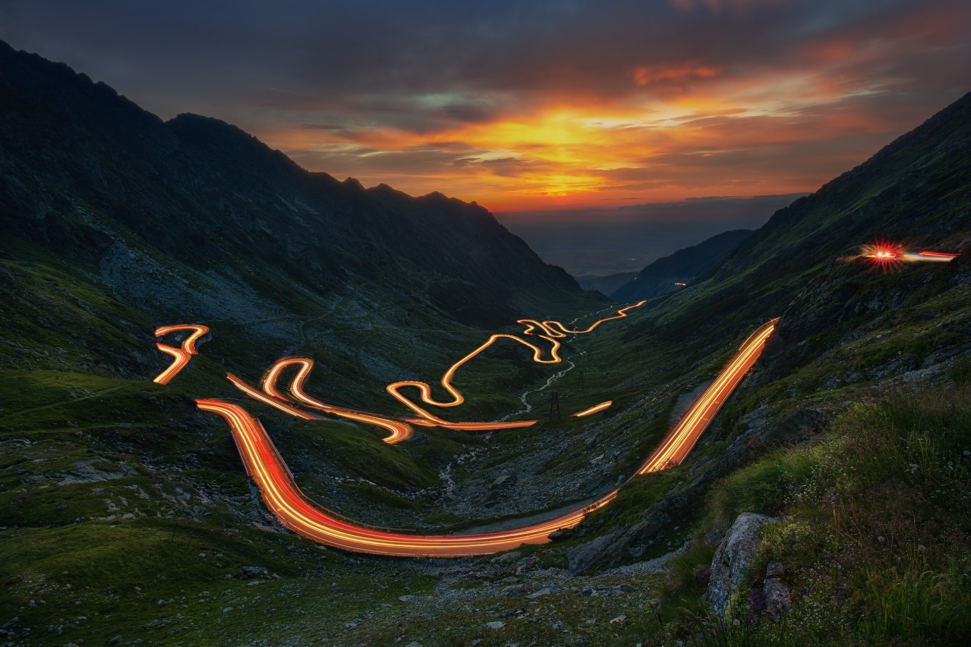 HD landscape photography of a winding mountain road at sunset with light trails, captured in a time-lapse style for a stunning PC desktop wallpaper background.