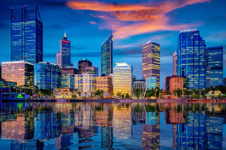 HD desktop wallpaper showcasing the vibrant Perth city skyline in Western Australia, with skyscrapers reflecting beautifully on the calm water at sunset.