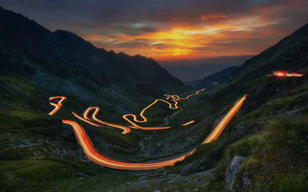 HD landscape photography of a winding mountain road at sunset with light trails, captured in a time-lapse style for a stunning PC desktop wallpaper background.