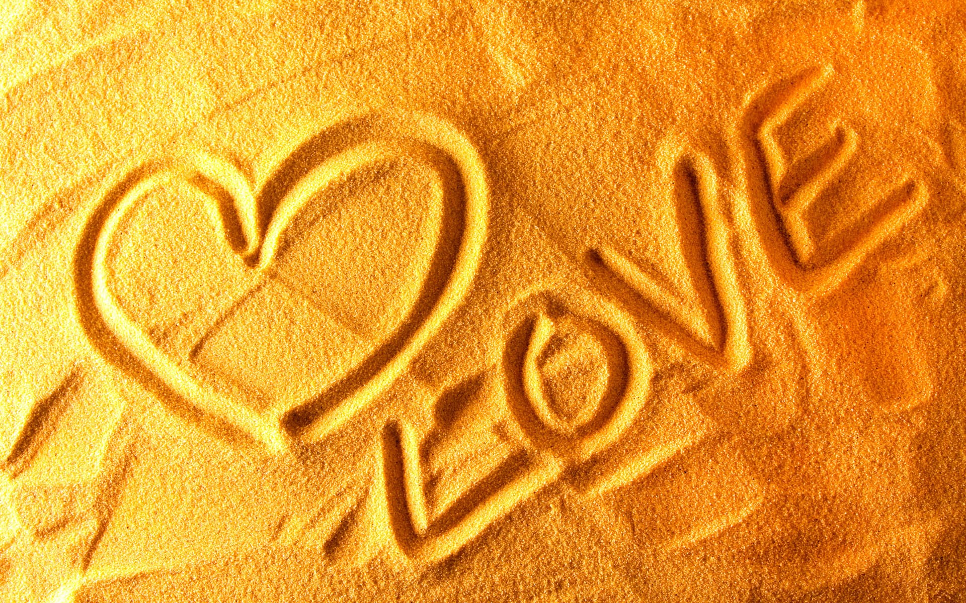 Heart and Love written in the sand on a beach.