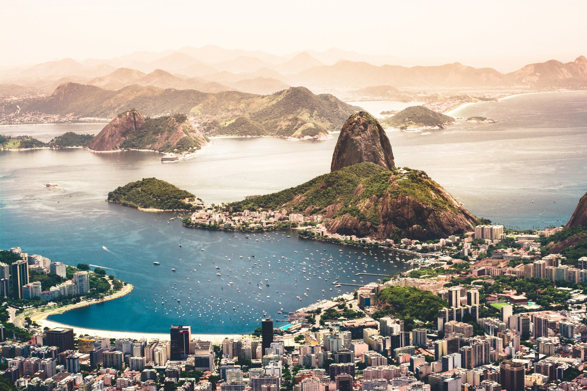 A stunning aerial view of Rio de Janeiro, Brazil, showcasing the cityscape and iconic mountains, with lush greenery and vibrant waters, captured in HD for a breathtaking desktop wallpaper.