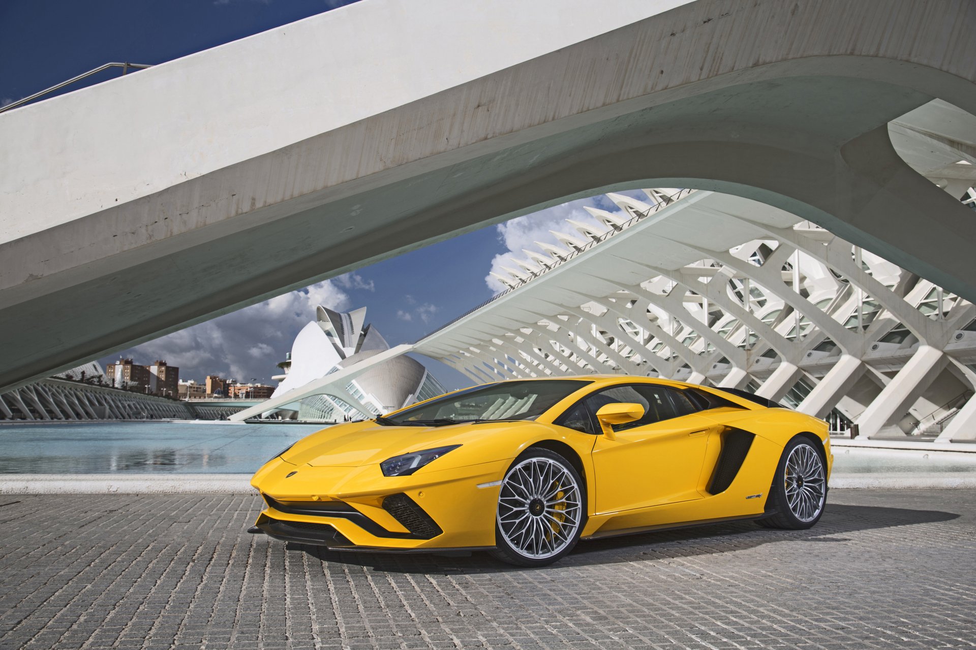 Yellow Lamborghini Aventador S supercar parked in front of a modern architectural structure, showcased in stunning 4K Ultra HD for PC desktop wallpaper and background.