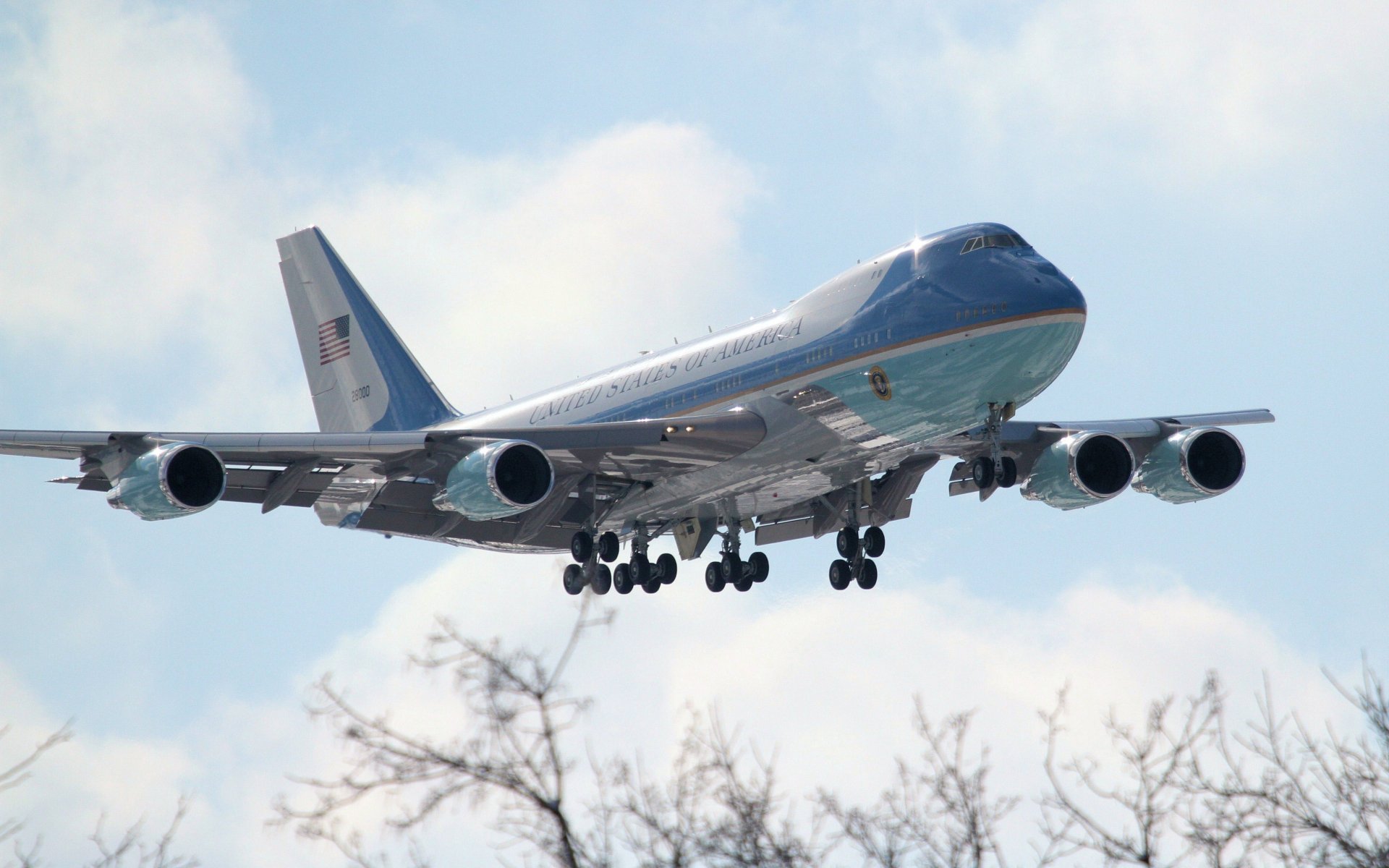 A Boeing VC-25 presidential aircraft, a modified Boeing 747 jet, captured in 4K Ultra HD as it descends against a partly cloudy sky.