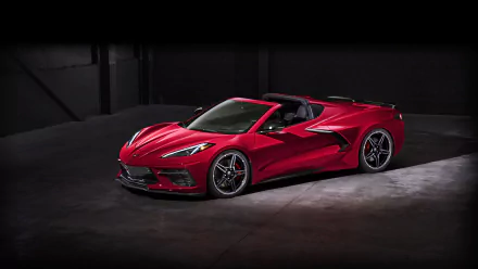 Red Chevrolet Corvette (C8) convertible vehicle in a dim studio, presented as an 8K Ultra HD PC desktop wallpaper.