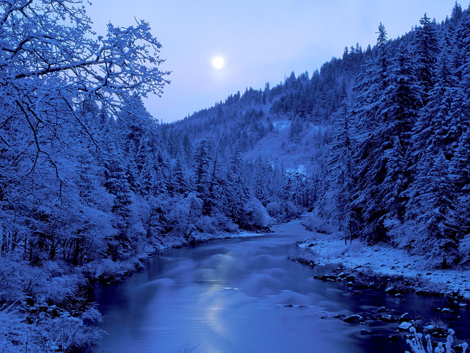 Snow-covered river reflecting the sun creates a serene winter landscape.