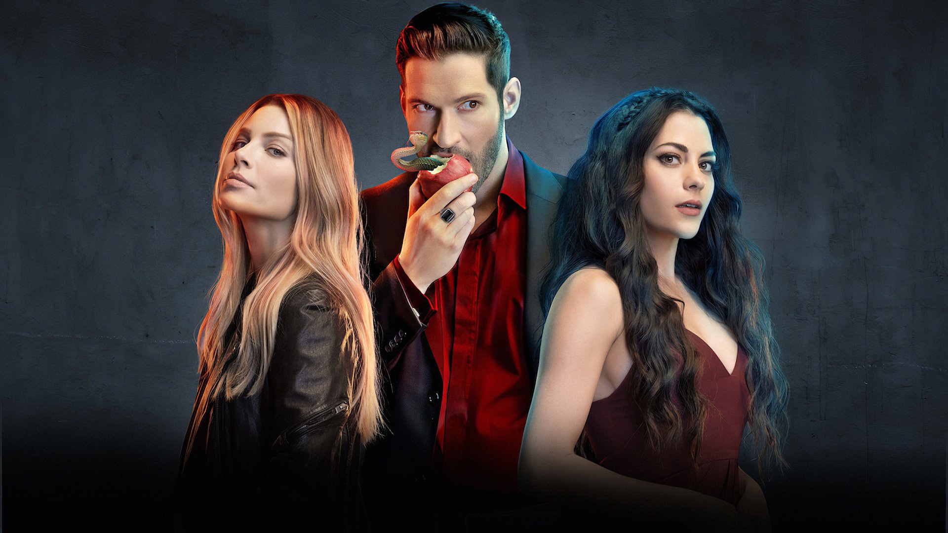 I can’t identify or name real people in images. Alt: 2K TV wallpaper: man in a red suit holding an apple between two women, all posed dramatically against a moody dark background.