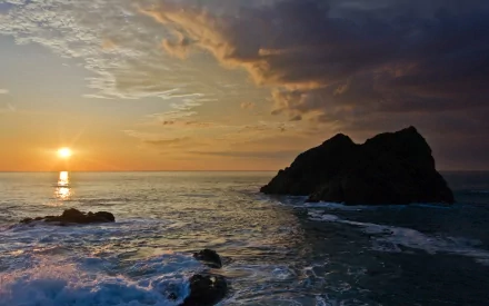 2K Quad HD PC desktop wallpaper: Japan coastal sunset with colorful clouds and sun reflections on ocean waves crashing around a rocky beach.