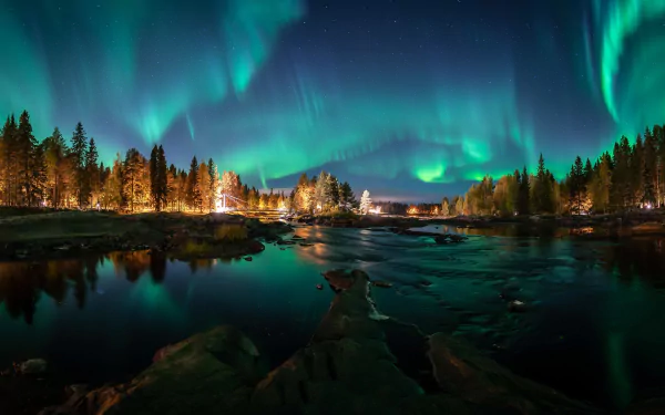Vibrant aurora borealis lights illuminate the night sky over a serene river and forest in Finland, creating a stunning HD nature desktop wallpaper.