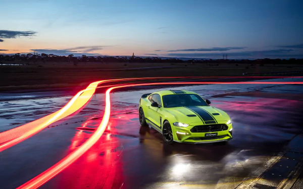 A green Ford Mustang R-Spec muscle car parked on wet pavement at dusk with time-lapse light trails, captured in 4K Ultra HD for a dynamic desktop wallpaper.
