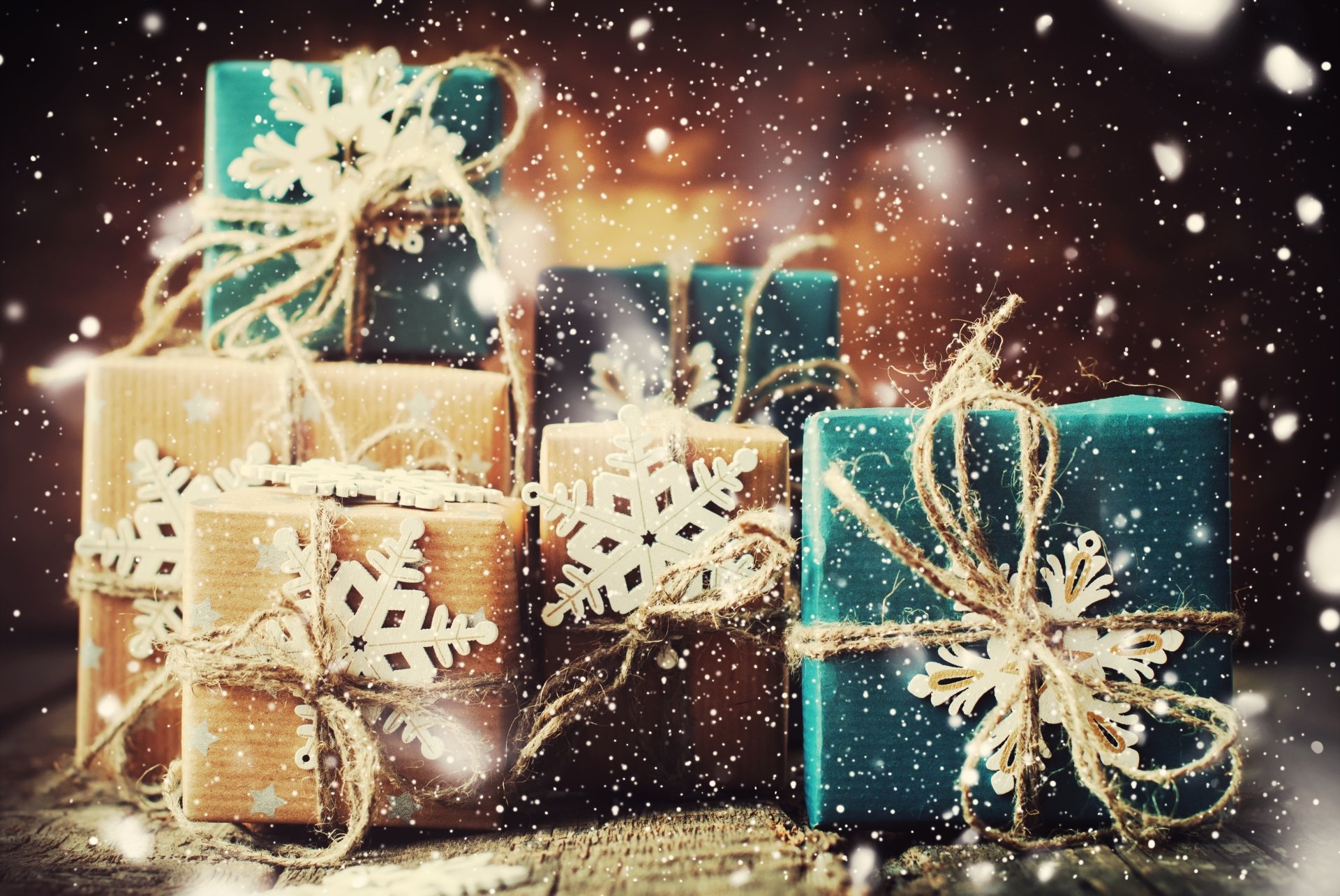 Misc, gift — 4K Ultra HD PC desktop wallpaper of teal and kraft-wrapped presents with twine and snowflake tags, falling snow and warm bokeh lights in the background.