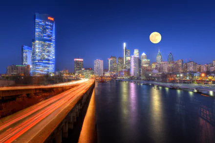 Nighttime view of Philadelphia’s skyscrapers and river under a full moon, captured in 4K Ultra HD as a vibrant cityscape and man-made skyline in the USA.
