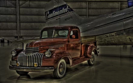 A vintage 1941 Chevrolet Pickup Truck stands in a hangar alongside an aircraft, showcasing classic design in this HDR HD wallpaper.