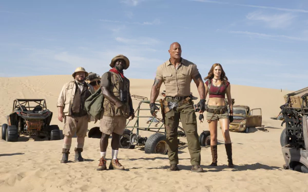 5K Ultra HD PC desktop wallpaper: four actors from Jumanji: The Next Level in desert adventure gear stand by dune buggies under a bright blue sky.