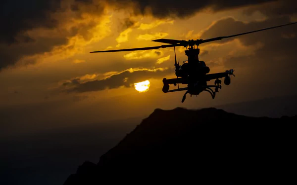 Silhouette of a Bell AH-1Z Viper attack helicopter flying against a dramatic sunset sky over rugged terrain, captured as an HD military-themed desktop wallpaper.