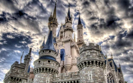 A dramatic view of a castle at Disneyland, featuring intricate architecture and towering spires, set against a moody sky, making it a stunning HD desktop wallpaper.