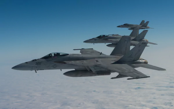 Two Boeing F/A-18E/F Super Hornet jet fighter warplanes fly above the clouds against a clear blue sky in a 4K Ultra HD military aircraft wallpaper.
