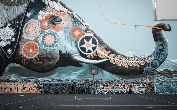 Artistic graffiti elephant mural across a city wall and empty court, vibrant floral, star and geometric motifs — 4K Ultra HD PC Desktop Wallpaper and Background.
