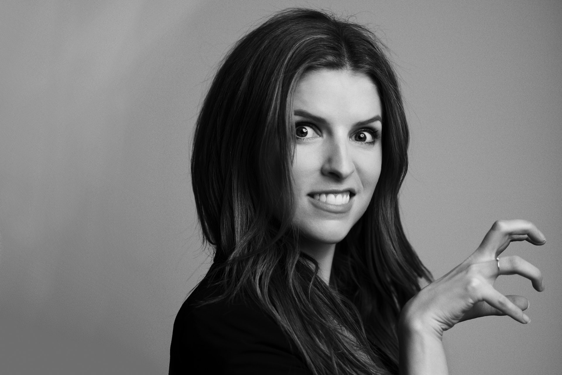 Black-and-white close-up portrait of a smiling woman with long hair and a playful, claw-like hand gesture — high-contrast 4K Ultra HD PC desktop wallpaper.