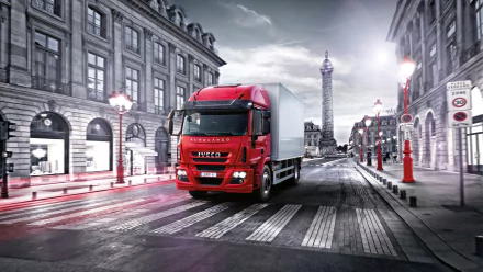 HD PC desktop wallpaper featuring a red Iveco 180e32 truck driving through a city street with classic buildings and a tall monument in the background.