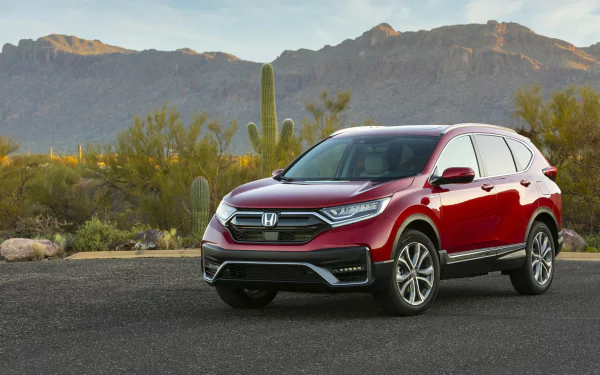 Red Honda CR-V compact SUV vehicle parked on a desert road with cacti and mountains at sunset — HD PC desktop wallpaper background.