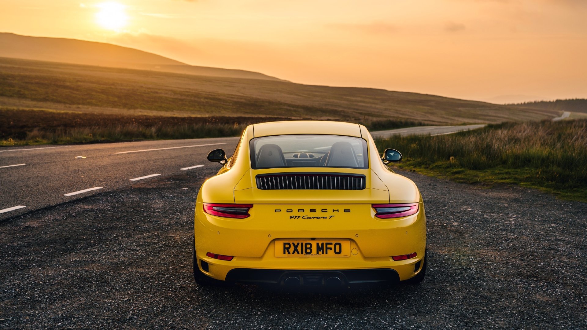 Rear view of a yellow Porsche 911 Carrera T on a winding road at sunset, 4K Ultra HD PC desktop wallpaper.