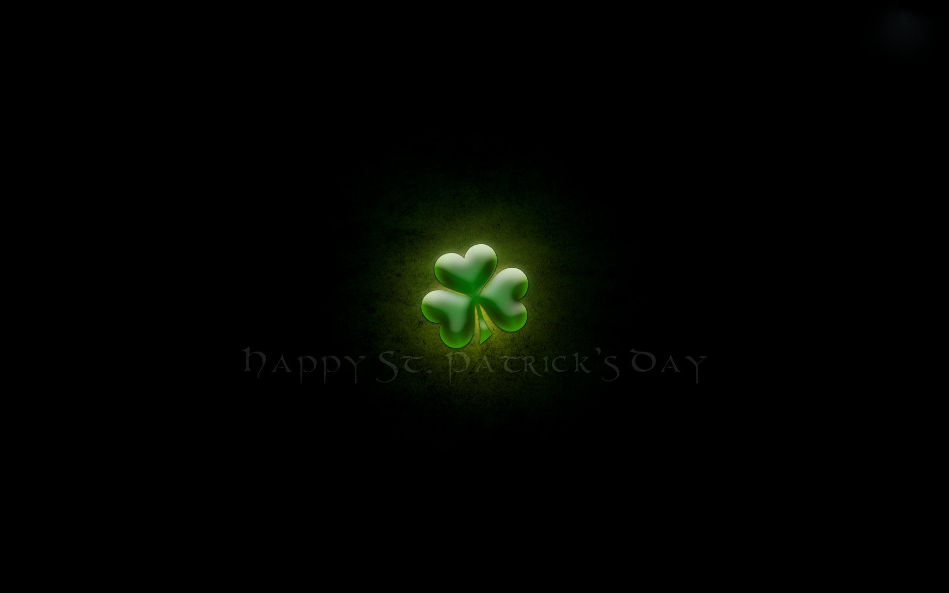 HD PC desktop wallpaper featuring a glowing green shamrock symbol celebrating the St. Patrick's Day holiday against a dark background.