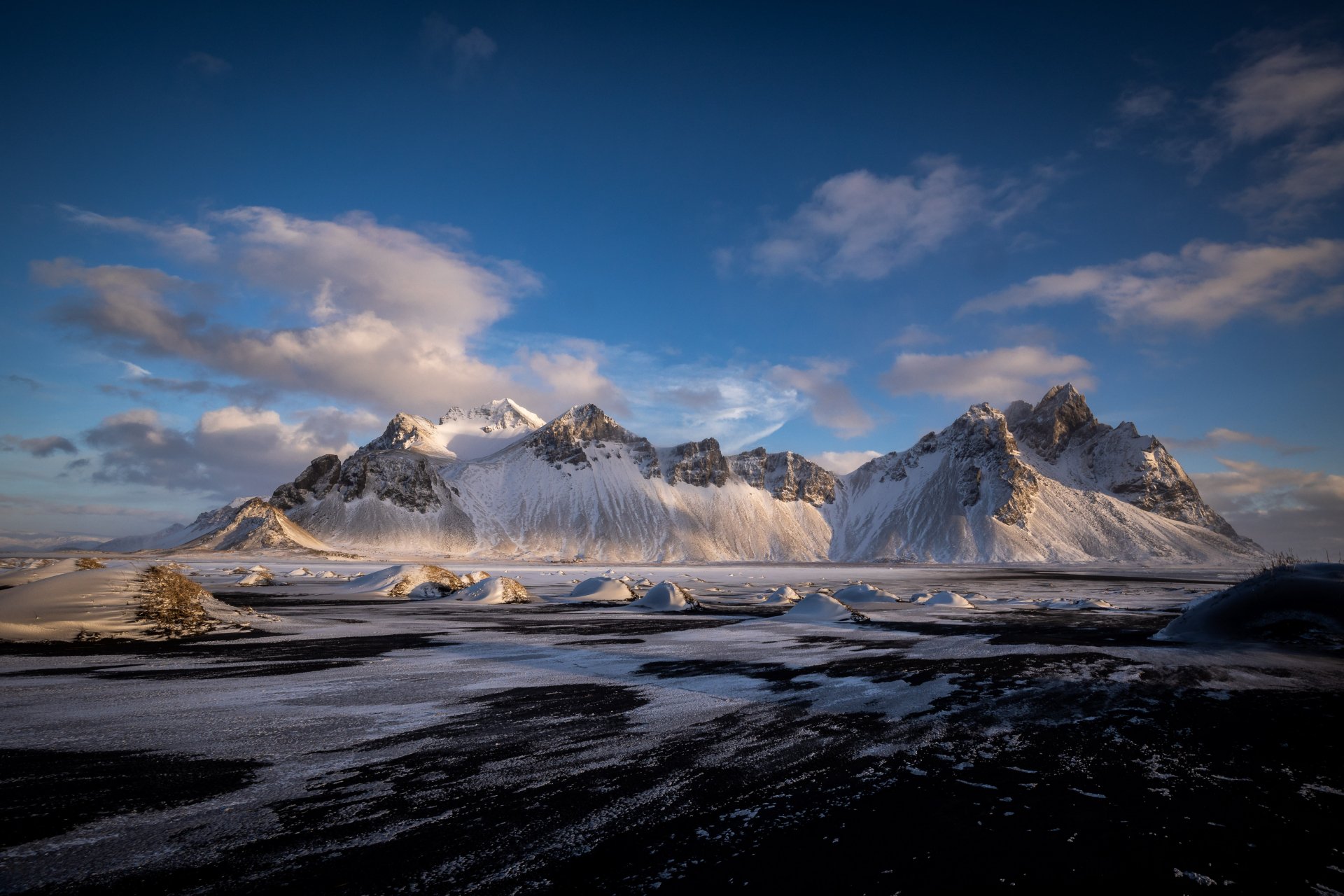 4K Ultra HD desktop wallpaper of Vestrahorn mountain, showcasing dramatic peaks and a contrasting dark shoreline under a vibrant sky in a stunning natural landscape.