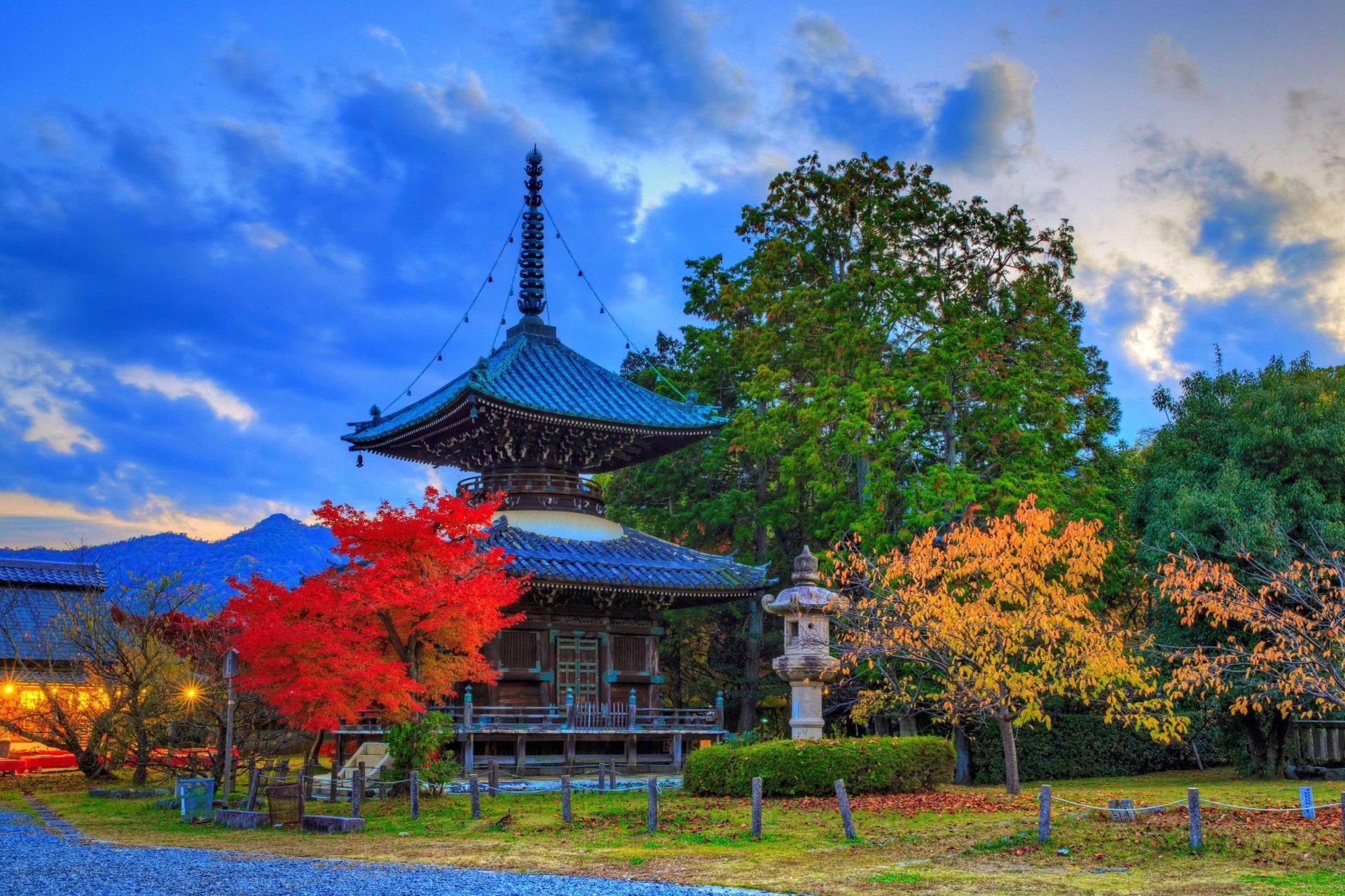 HD desktop wallpaper of a serene Kyoto temple in Japan, surrounded by vibrant fall foliage under a dramatic blue sky.