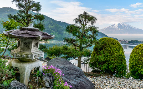 5K Ultra HD PC desktop wallpaper of Mount Fuji in Japan: tranquil mountain and lakeside garden with a stone lantern, evergreens, rocks, and blooming flowers.