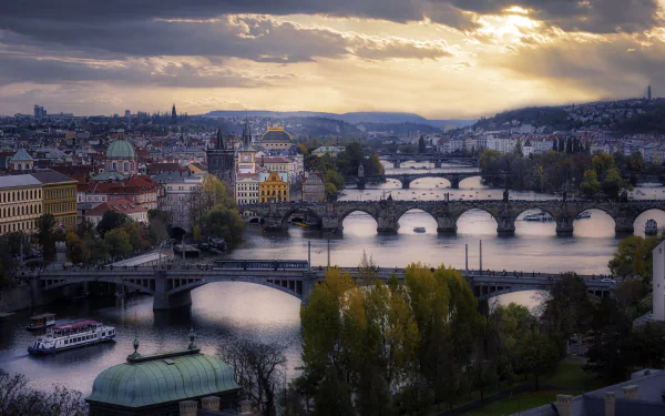 4K Ultra HD view of Prague featuring multiple historic bridges over a river, set against a dramatic sky, highlighting the city's iconic man-made architecture and urban landscape.