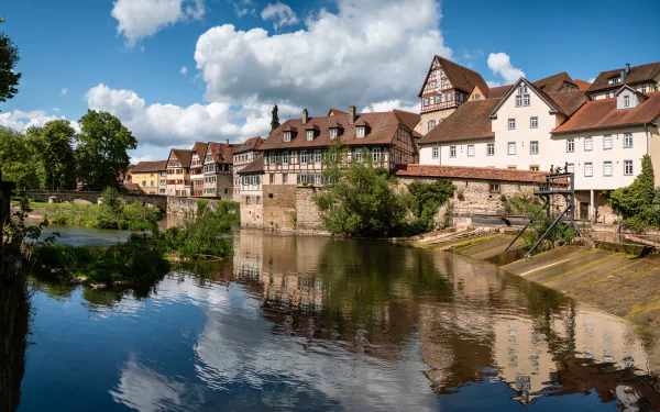 Scenic view of traditional houses along a river in Baden-Württemberg, Germany, with reflections and clouds in the water, captured as an HD desktop wallpaper background.