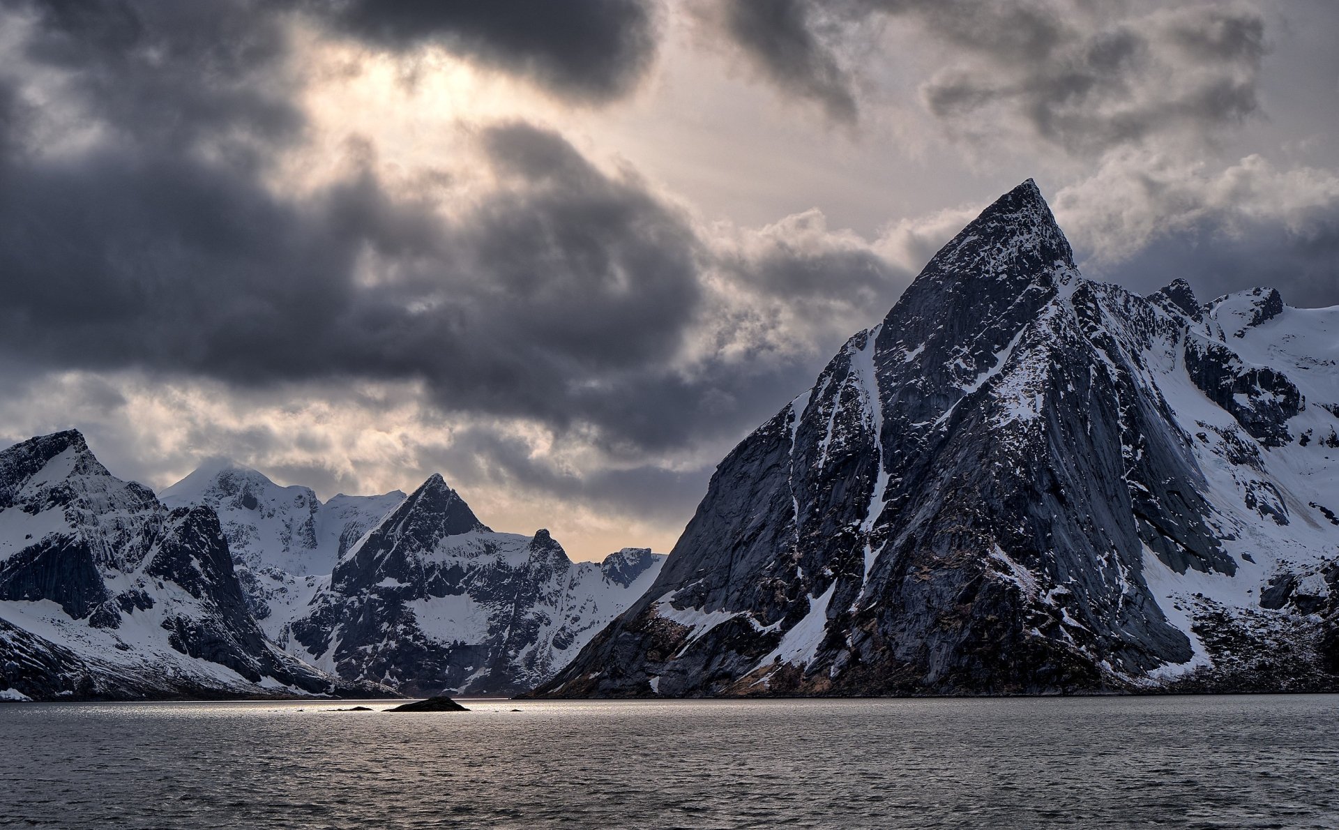 HD photography of dramatic snow-covered mountains under a cloudy sky in Lofoten, captured as a striking PC desktop wallpaper and background.