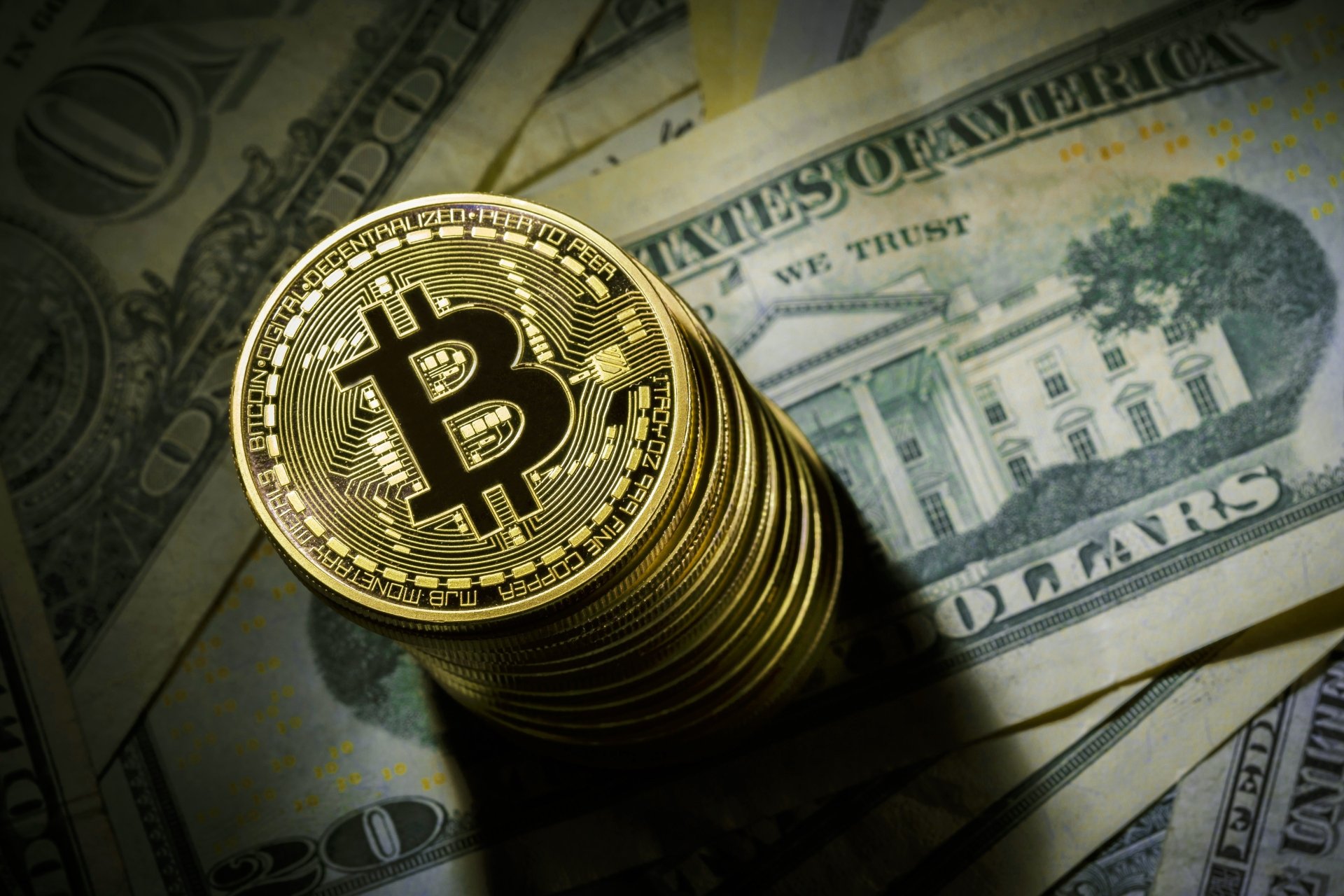 Stack of golden Bitcoin coins placed on US dollar bills, symbolizing the fusion of digital cryptocurrency and traditional money, captured in 4K Ultra HD detail.