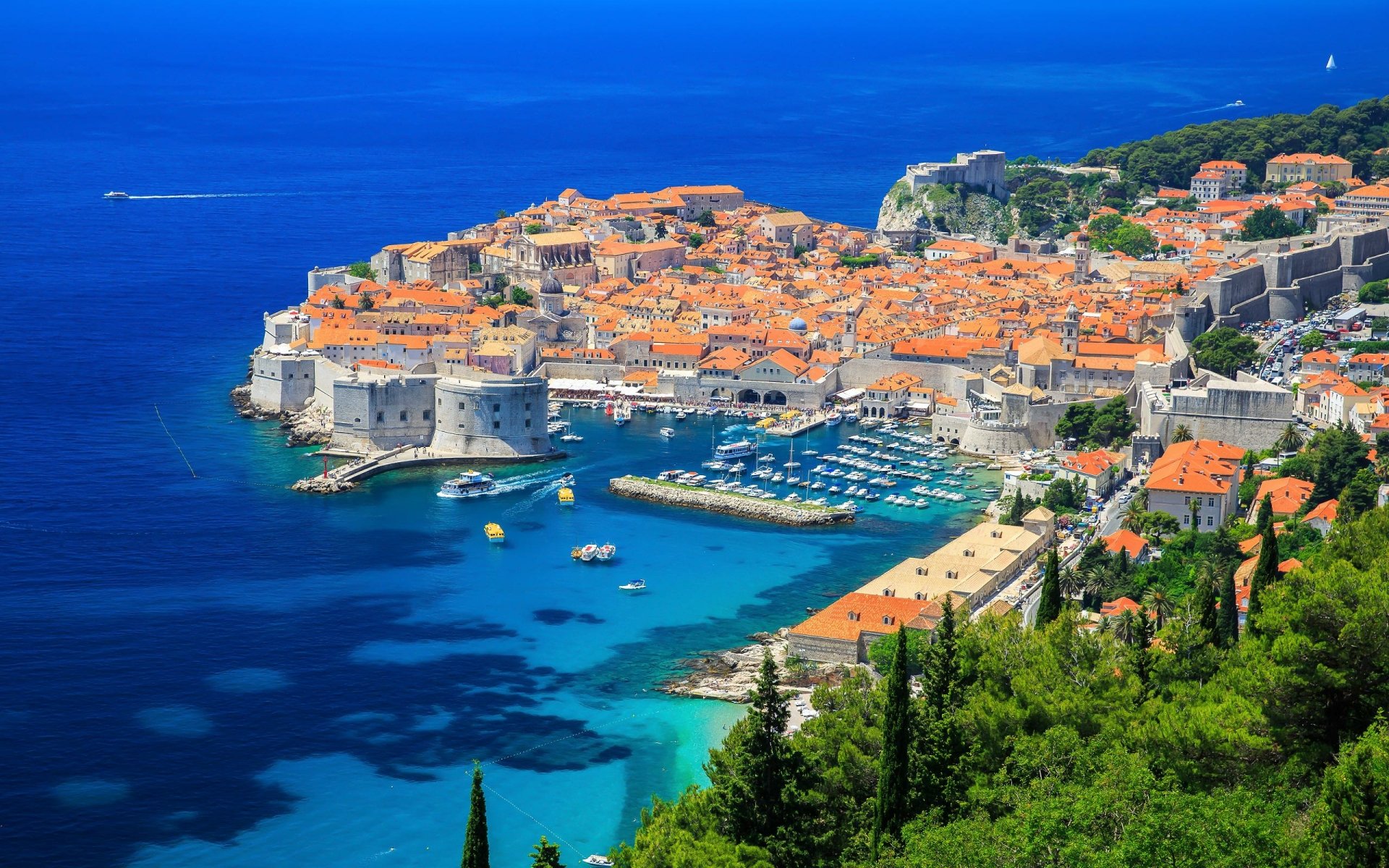 Aerial view of Dubrovnik, Croatia: the walled coastal city with terracotta roofs and marina beside the deep blue Adriatic — 2K Quad HD PC desktop wallpaper.