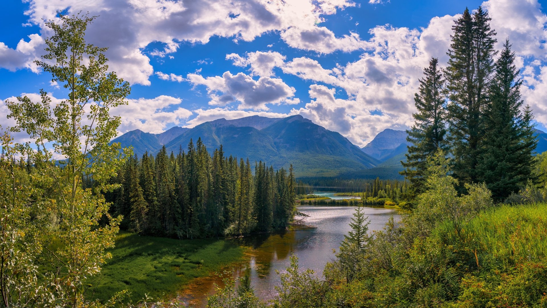 Alberta, Canada 4K Ultra HD PC desktop wallpaper — mountain landscape with forested river valley and dramatic cloud-filled sky over distant peaks.