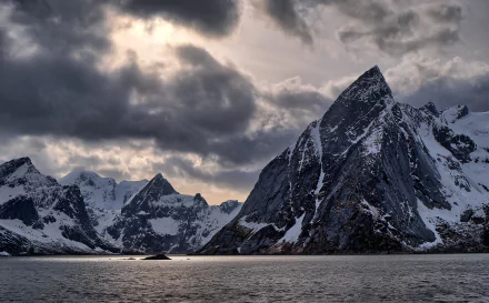 HD photography of dramatic snow-covered mountains under a cloudy sky in Lofoten, captured as a striking PC desktop wallpaper and background.