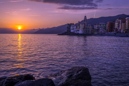 Sunset over the Ligurian Sea with a coastal town in Italy, featuring calm waters and a serene sky in this 4K Ultra HD desktop wallpaper.