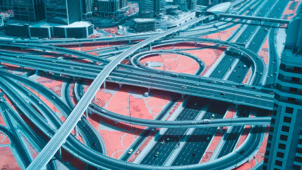 Aerial photography of a Dubai highway interchange with layered overpasses and flowing traffic — 4K Ultra HD PC desktop wallpaper/background.